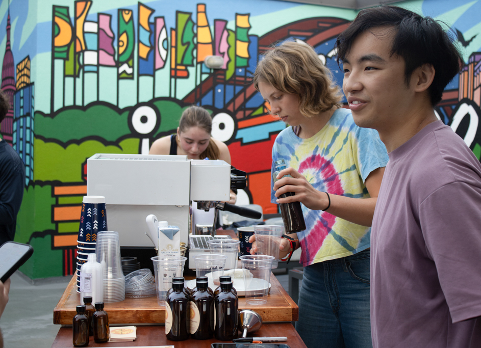 Catie Nunn, Saja Drink co-founder and exercise science senior, prepares a latte, while Jason Wang, co-founder and chemical engineering senior talks to a guest at the Block on 25th rooftop on March 5.  