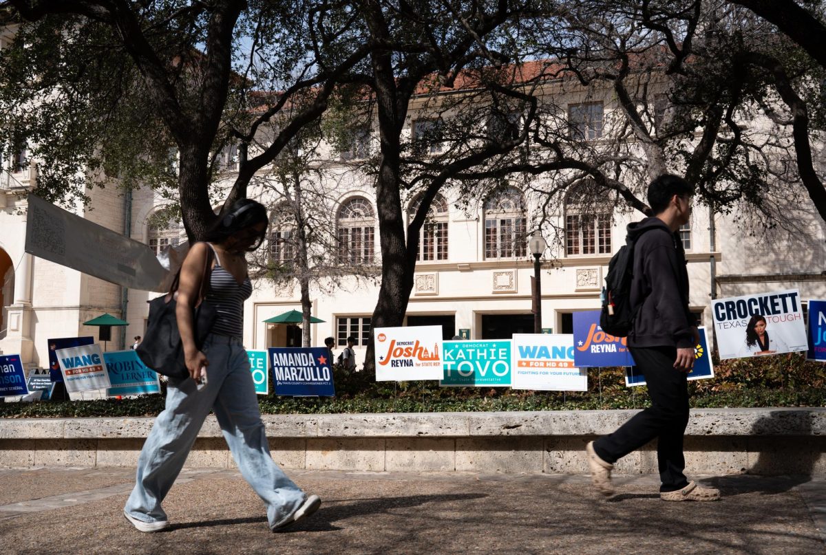 Students walk past campaign signs in front of the Texas Union on Feb. 25.