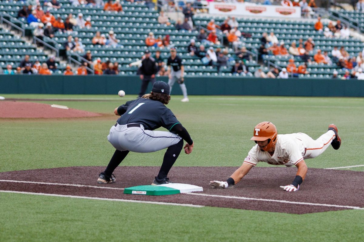Senior infielder Temo Becerra dives safely back to first base after a pickoff attempt at Texas' game against USC Upstate at Disch-Falk Field on March 8.