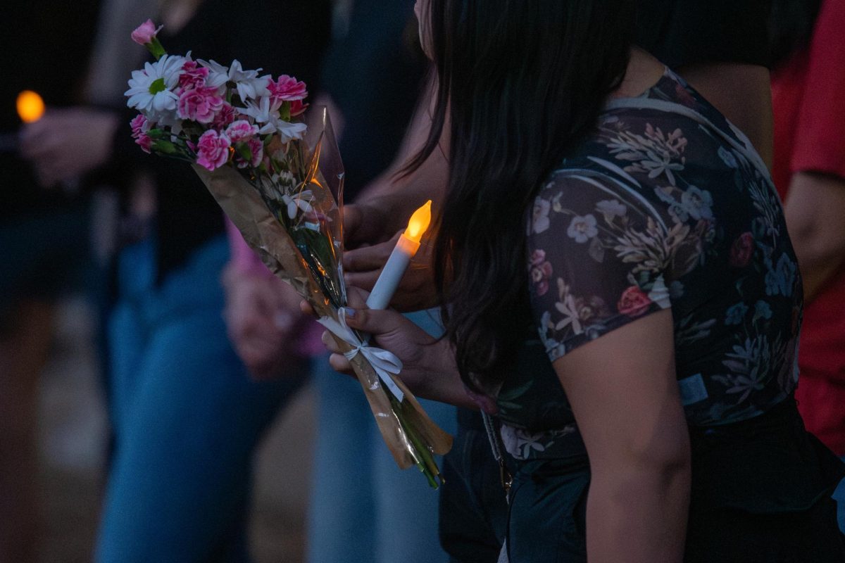 A student holds a bouquet of flowers and a candle at the West 6th Street shooting vigil on Tuesday, Mar. 3. Students Demand Action organized the vigil and created a memorial for students to lay flowers.