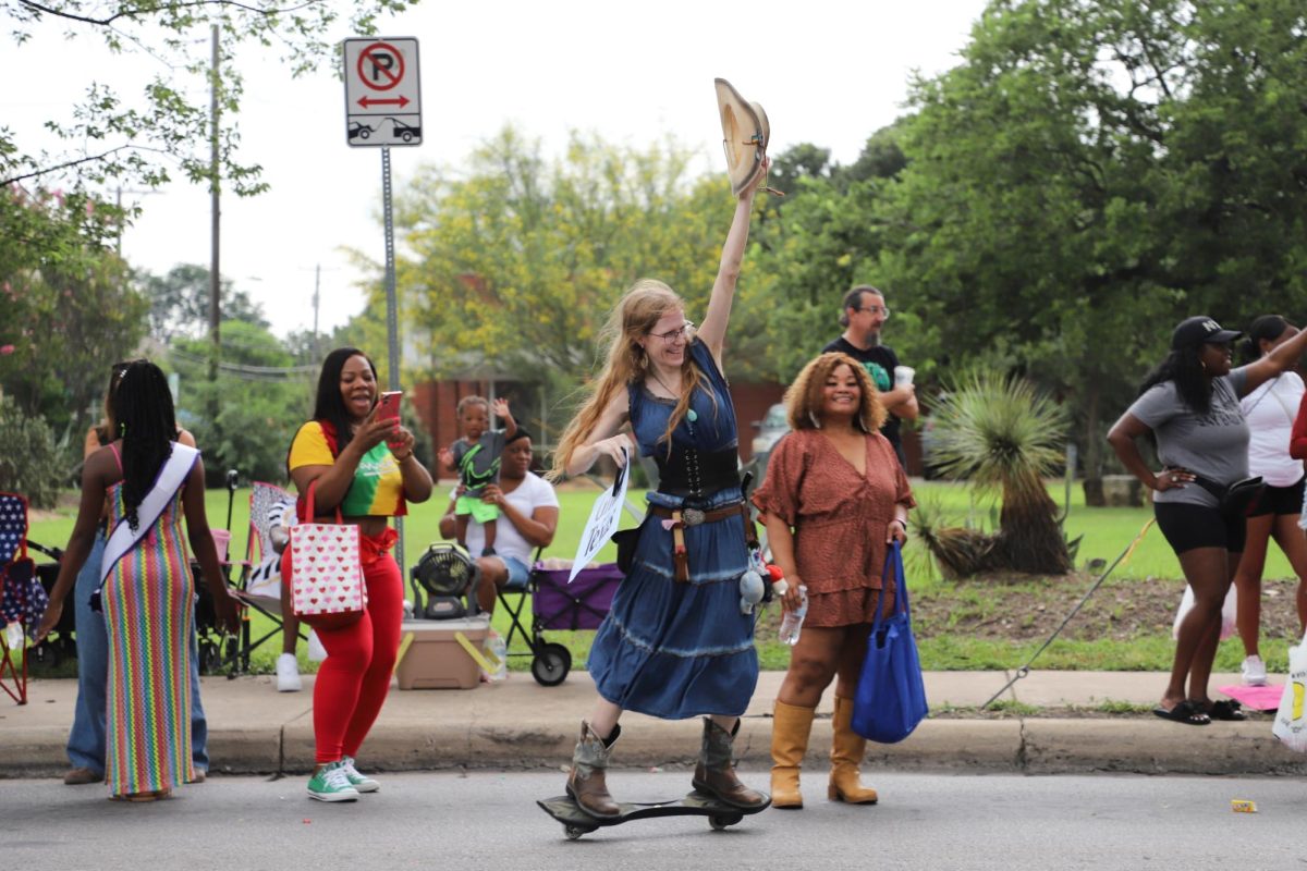 A woman rides a caster board while carrying a “Gina for Texas” sign during the Central Texas Juneteenth Parade on Friday, June 19.