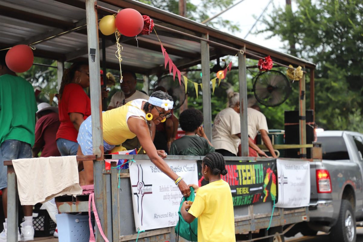 A woman hands candy to a girl during the Central Texas Juneteenth parade on Friday, June 19.
