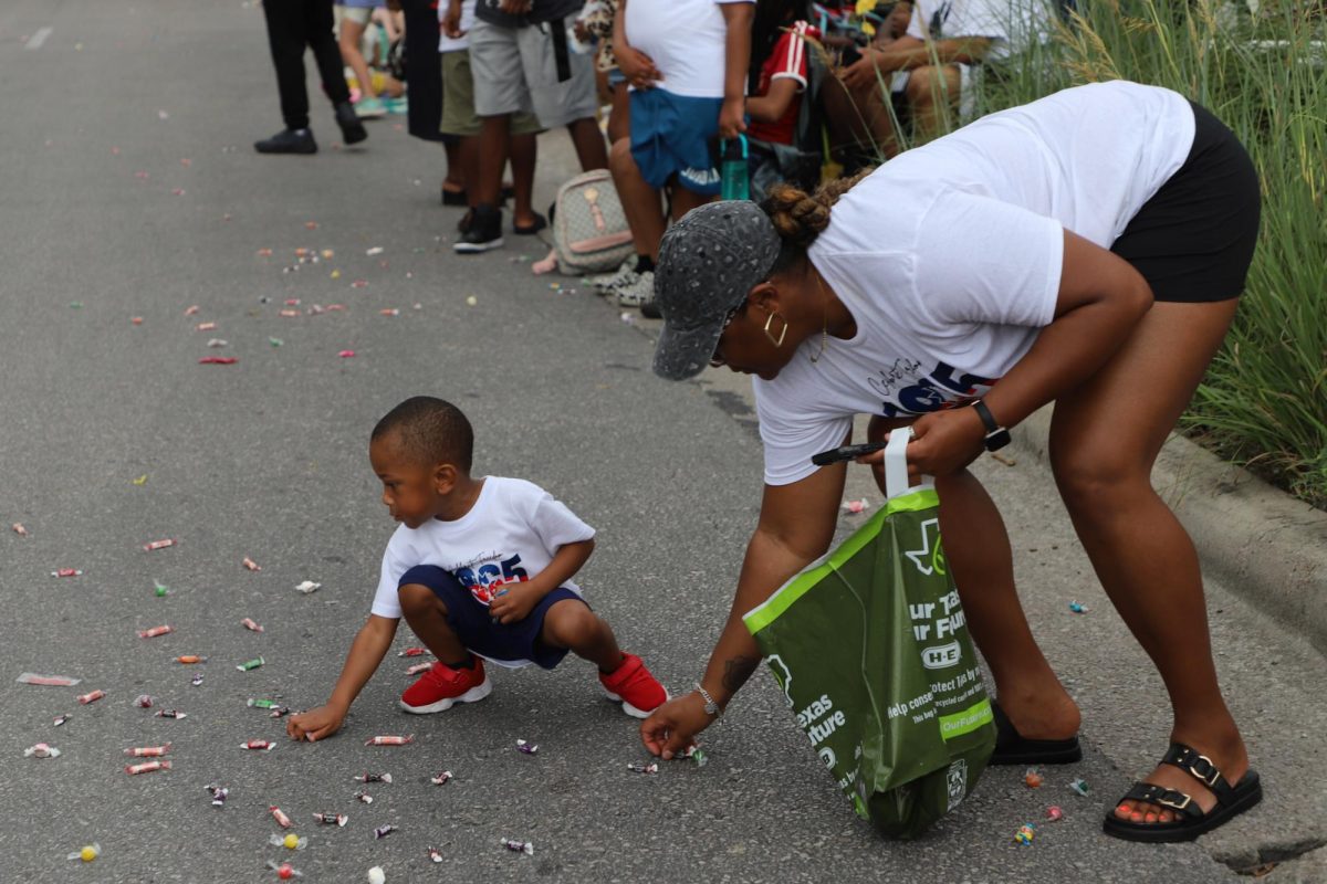 A little boy and a woman crouch down to pick up candy at the Central Texas Juneteenth Parade on Friday, June 19.