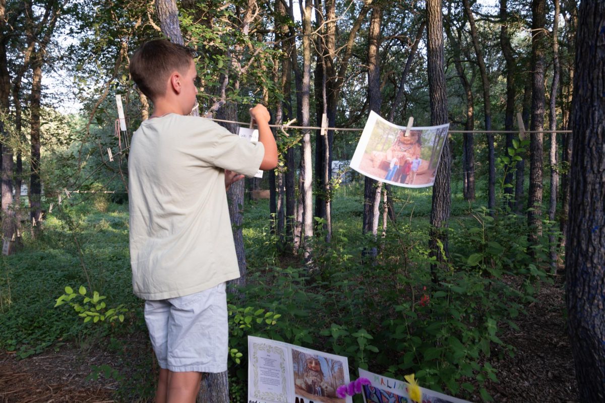 A boy hangs a card for Malin during the "An Evening for Malin" memorial in Pease Park on Wednesday, June 24. 