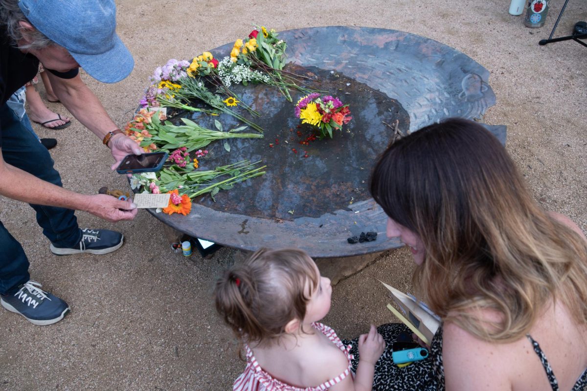 Attendees of the "An Evening for Malin" memorial pictured around Malin the Fountain trolls water dish in Pease Park on Wednesday, June 24.  The memorial honors the Malin's Fountain troll sculpture that burned down in a fire the morning of May 21, after residing in the park for over two years. 